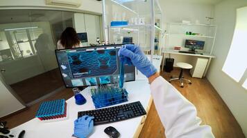 FPV of biologist doctor checking liquide from test tubes, writing on pc, while colleague bringing blood samples. Scientists examining vaccine evolution in medical lab using high tech for research. photo