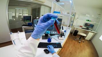 POV of scientist analysing blood sample from test tube typing on computer. Viorolog researcher in professional lab working to discover medical treatment, team of doctors analysing vaccine evolution photo