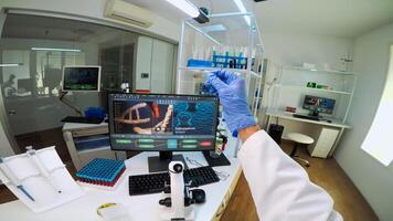 POV of scientist looking at biological samples under microscope typing on pc. Team of chemists working in lab, examining virus evolution using high tech for scientific research of vaccine development. photo