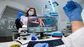 Team of microbiology scientists discussing about virus development in equipped laboratory using computer analysing test blood samples and develop vaccine, drugs and antibiotics against covid-19. photo