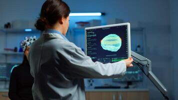 Neurologist doctor reading informations of patient looking at monitor analysing brain scan discussing with patient wearing eeg headset. Scientist taking notes examining nervous system of woman in lab photo