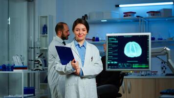 Portrait of scientist neurologist researcher looking at camera smiling while coworker discussing with patient in background about brain functions, nervous system, tomography scan working in laboratory photo