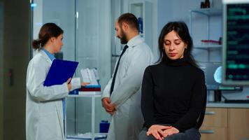 Team of scientists doctor discussing health status of patient, brain functions, nervous system, tomography scan while woman waiting for diagnosis of disease sitting in neurological research laboratory photo