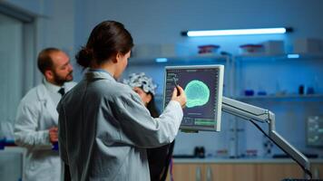 Researcher looking at monitor analysing brain scan while coworker discussing with patient in background about side effects, mind functions, nervous system, tomography scan working in laboratory photo