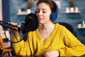 Creative influencer with headphones preparing to speak during live on social media recording vlog. On-air online production internet broadcast show host streaming podcast content from studio. photo