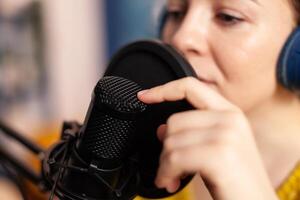 Influencer talking on professional microphone during livestreaming recording vlog in living room. On-air online production internet broadcast show host streaming live content for social media. photo