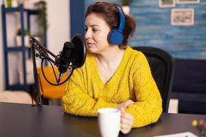 Influencer wearing headphones recording new podcast series for audience. On-air online production internet broadcast show host streaming live content for digital social media using internet web. photo