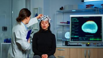 Neurological doctor cheking eeg headset explaining to patient diagnosis of disease and treatment for nervous system. Scientist researcher analysing brain scan and tomography on monitor in lab photo