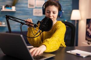 Vlogger looking at laptop and asking audience to subscribe on her channel. Online show On-air production internet broadcast host streaming live content, recording digital social media communication. photo