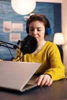 Blogger opening laptop starting to talk with followers recording new podcast at home studio. On-air online production internet broadcast show host streaming live content, recording digital vlog. photo