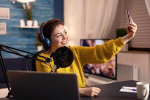 Entertainment blogger doing selfie during broadcast working from home studio. On-air online production internet podcast show host streaming live content, recording digital social media communication. photo