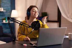 Vlogger speaking with follower on live using professional microphone wearing headphones. Creative online show On-air production internet broadcast host streaming live content, recording digital social. photo