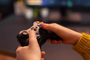 Close-up of professional cyber gamer holding joystick playing space shooter game. Pro player use equipment during gaming tournament late at night in home studio using wireless controller photo