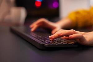 Close-up on hands of woman gamer playing game using keyboard. Virtual championship in cyberspace, esports player performing on pc during gaming tournament using technology network wireless. photo