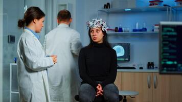 Expert medic in neuroscience developing brain experiment holding laptop explaning to woman side effects of nervous system treamtment. Team of scientists working in neurological research laboratory photo
