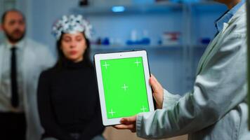 Health care researcher holding and looking at tablet with chroma key display in neurological lab. Team of scientists doing medical research reading on device with green screen, isolated mockup display photo