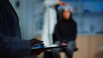 Close up of expert scientist in neurological dysfunctions standing in laboratory working at tablet. Medical researcher preparing patient for brain scan analysing electrical activity of nervous system photo