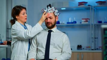 Neurologist doctor analysing brain of man and nervous system using brainwave scanning headset. Researcher using high tech developing neurological innovation monitoring side effects on monitor screen photo