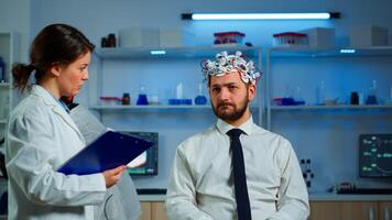 Researcher neurologist doctor asking man's symptoms taking notes on clipboard before brain scan with brainwave scanning headset. Scientist analyzing health status, nervous system, tomography scan photo