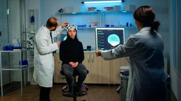 Man doctor examining sensors of eeg headset, monitoring brain functions, while medical researcher analysing tomography scan on monitor, working in scientific neurological laboratory photo