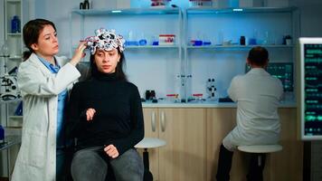 Medical lab technician adjusting eeg headset monitoring brain functions, descovering diagnosis of disease. Team of scientists researchers working late night in neurology clinic for woman health photo