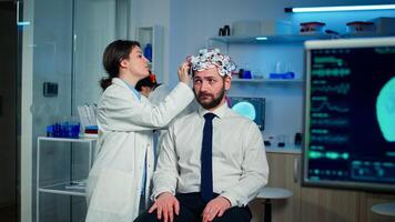Man patient visiting professional medical researcher in neurology medicine testing brain functions with eeg headset. Doctor monitoring nervous system, descovering diagnosis of disease. photo