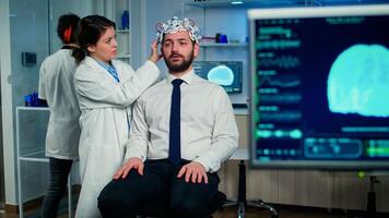 Medical researcher putting performant brainwave scanning headset monitoring brain functions in medical neurological laboratory with monitor showing eeg scan. Treating nervous system dysfunctions photo