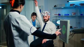 Man patient with high tech headset device participating at neurological experiment in technologically advanced laboratory testing physical reactions and nervous system photo