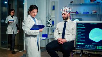 Medical doctor talking about symptoms of disease during investigations using high tech brainwave scanning headset. Researcher analysing health status of man patient, brain functions, nervous system photo