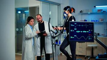 Professional scientist analysing EKG results looking at monitor examining heart rate of athlete. Team of researchers monitoring endurance, vo2 max, psychological resistance in science sport laboratory photo