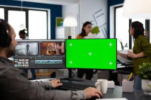 editor using computer with chroma key, mock up isolated display editing project and audio footage. Videographer editor processing film montage on pc with green screen photo