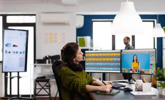 Creative photographer using digital retouching software, wearing headphones editing photos for client. Stylish retoucher, graphic editor working in creative multimedia workplace