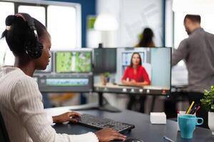 editor in web online conference with project creator on call editing business client work, getting feedback on movie using post production software on two monitors in start up office photo