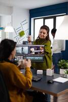 Women videographers editing project creating multimedia content, team of bloggers working in modern creativity office studio. Manager explaning to colleaque film montage discussing production photo