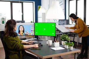Woman digital artist working editing creative photo using greenscreen, chroma key isolated display of computer. Photographer retoucher creator doing portrait retouching in multimedia company