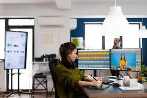 Creative photographer using digital retouching software, wearing headphones editing photos for client. Stylish retoucher, graphic editor working in creative multimedia workplace