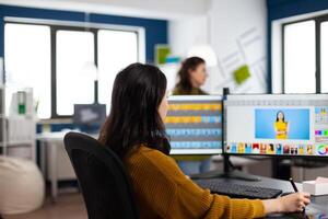 Caucasian photographer woman sitting at desk listening music using PC in studio agency office. Designer content creator doing portrait retouching using post production software photo
