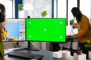Woman digital artist working editing creative photo using greenscreen, chroma key isolated display of computer. Photographer retoucher creator doing portrait retouching in multimedia company