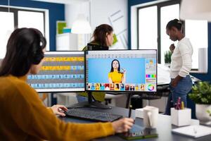 Caucasian photographer woman sitting at desk listening music using PC in studio agency office. Designer content creator doing portrait retouching using post production software photo
