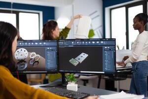 Industrial engineer woman working at pc with two monitors, screens showing CAD software with 3D architecture prototype of gears mechanical piece. Entrepreneur working in creative construction office photo