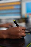 Close up of black designer editing customer client image with stylus pencil, drawing on graphics tablet. Hand of african american woman editor photographer retouching assets working in creative production company office photo