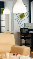 Interior of cozy light company room with small table and confortable couch, modern stylish chairs and desktop computer, all ready for employees. Empty spacious office of creative working space. photo