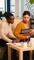 Multiethnic team analysing informations from tablet discussing sitting on couch brainstorming on new project for start up company. Diverse businesspeople analysing financial reports during meeting. photo