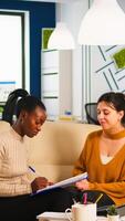 Diverse businesswomen discussing new project for company evolution, black woman checking tasks on clipboard, signing new contract. Multiethnic employees gathered in co-working space photo