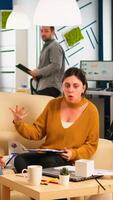 Stressed busineswomen arguing, yealing at each other during work hours sitting on the couch, while diverse colleagues working scared in background. Women throwing papers, conflicts at work concept photo