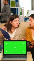 International business team talking to african woman discussing company plan with mockup laptop in front of camera. Leader explainig project strategy using green screen pc with chroma key display. photo