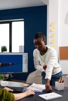 Multiethnic women designer looking at computer with dual displays working together at gaming project in startup office. Gamer workers developing digital games on pc with modern technology photo