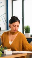 Satisfied manager checking financial statistics and graphs typing on laptop sitting at desk working in financial startup company. Diverse team analyzes statistics data in modern office photo