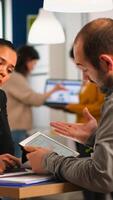 Close up of diverse business team checking graphs from tablet making new strategy. Manager explaining to multiethnic colleagues new financial project sitting at desk in moder startup office photo