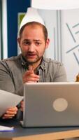 Colleagues sitting at desk, working with laptop computer, showing first project results to confident boss team leader explaining financial strategy. Diverse business partners developing startup idea. photo